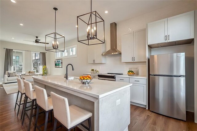 kitchen with sink, hanging light fixtures, a kitchen island with sink, stainless steel dishwasher, and dark wood-type flooring