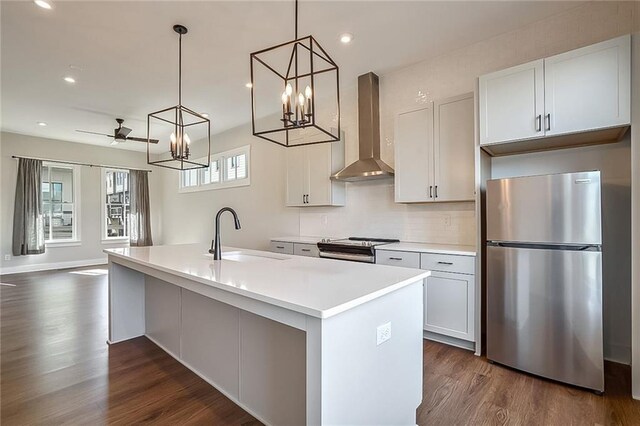 kitchen featuring sink, backsplash, stainless steel appliances, decorative light fixtures, and wall chimney exhaust hood