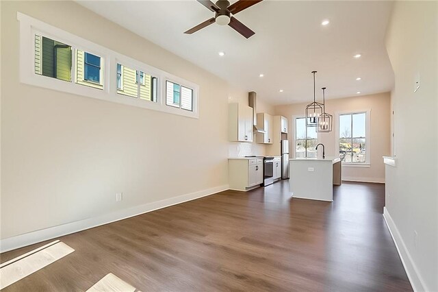 unfurnished living room with dark wood-type flooring, sink, and ceiling fan