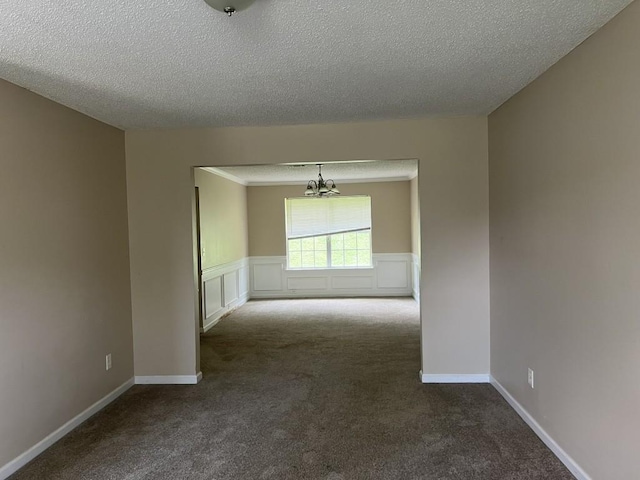 6157 Redtop Loop, Fairburn, GA 30213 - unfurnished room featuring dark carpet, a chandelier, a textured ceiling, and a wainscoted wall
