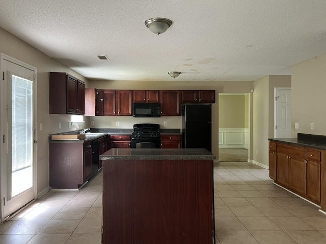 6157 Redtop Loop, Fairburn, GA 30213 - kitchen featuring black appliances, dark countertops, light tile patterned flooring, a textured ceiling, and a kitchen island