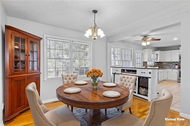 dining room featuring light wood-type flooring, visible vents, baseboards, and ceiling fan with notable chandelier