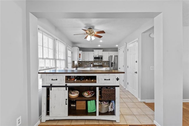 kitchen with tasteful backsplash, white cabinets, wood counters, appliances with stainless steel finishes, and a sink