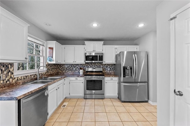 kitchen with stainless steel appliances, backsplash, dark countertops, and a sink