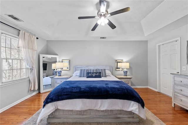 bedroom with baseboards, visible vents, and wood finished floors