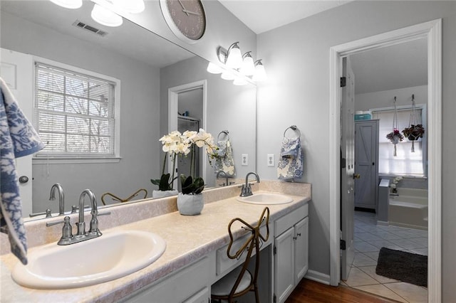 full bath featuring double vanity, visible vents, a sink, and tile patterned floors