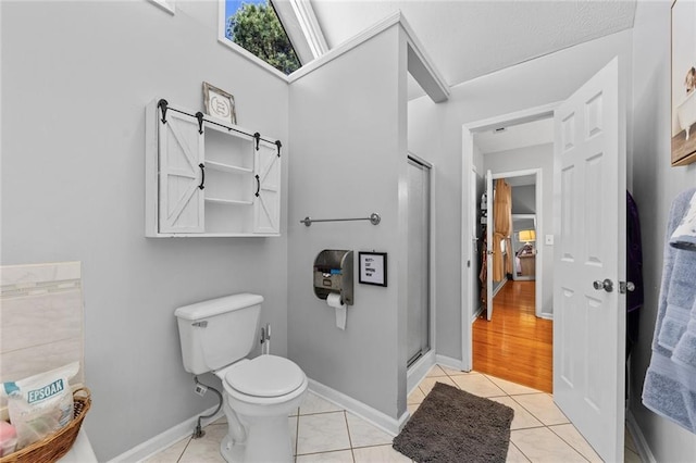 full bath with baseboards, tile patterned flooring, toilet, and a shower stall