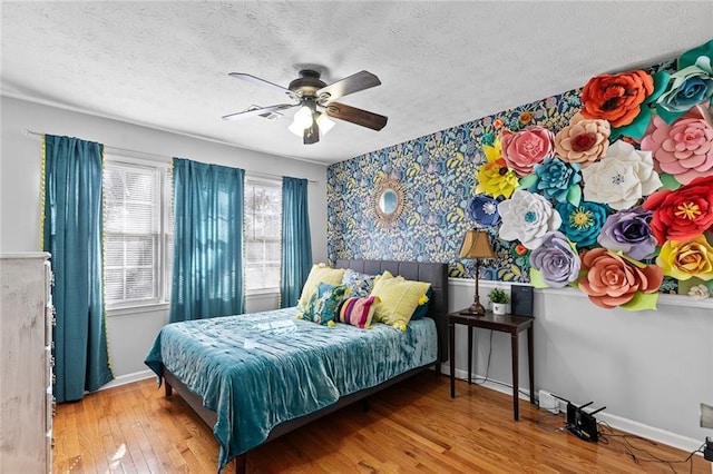 bedroom with wood-type flooring, ceiling fan, a textured ceiling, and baseboards