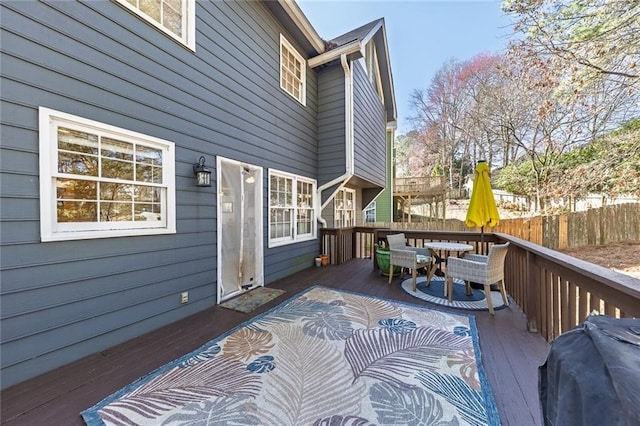 wooden terrace with outdoor dining space, area for grilling, and fence