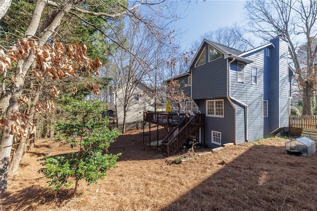 rear view of house with a chimney, stairway, fence, and a wooden deck