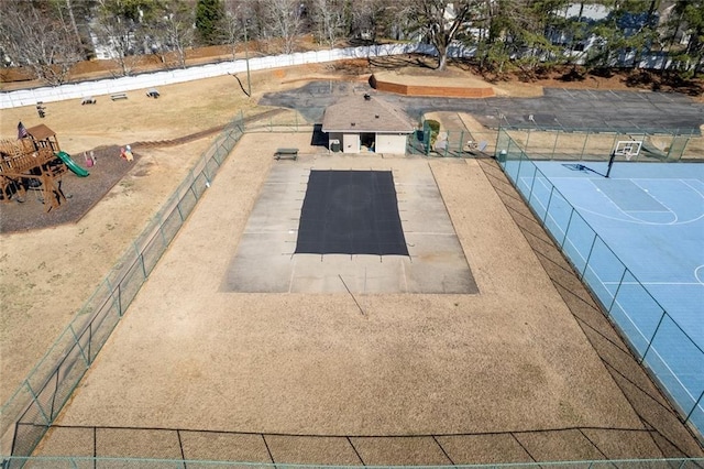 exterior space featuring a tennis court, fence, and playground community