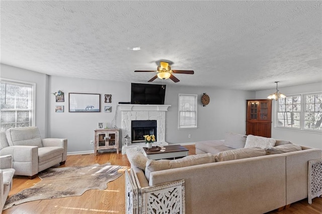 living area with plenty of natural light, light wood-style flooring, and a stone fireplace