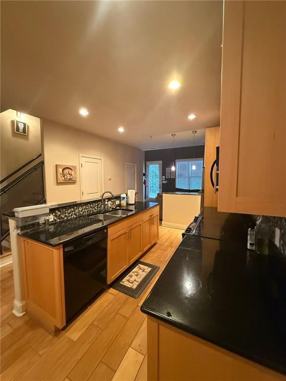 kitchen featuring sink, light brown cabinets, light wood-type flooring, black dishwasher, and kitchen peninsula