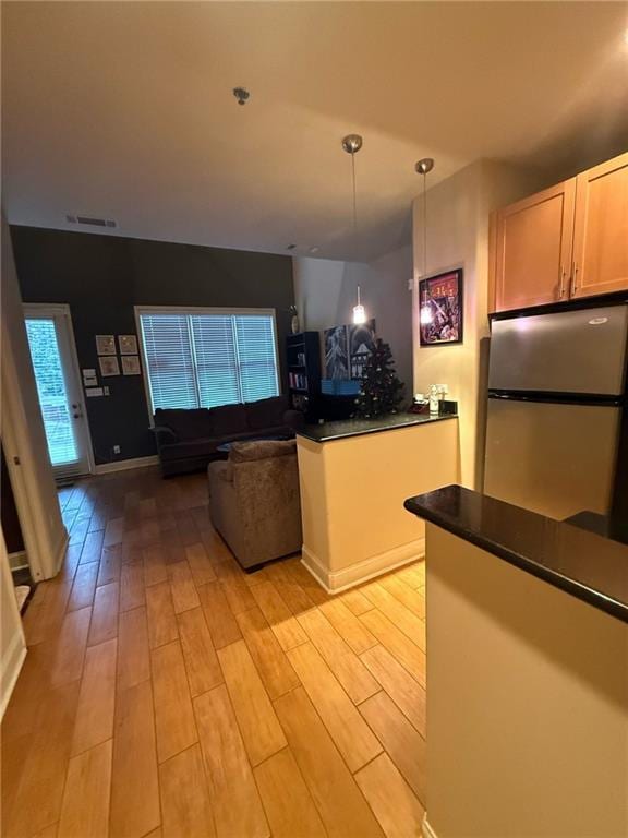 kitchen with decorative light fixtures, light hardwood / wood-style flooring, and stainless steel refrigerator