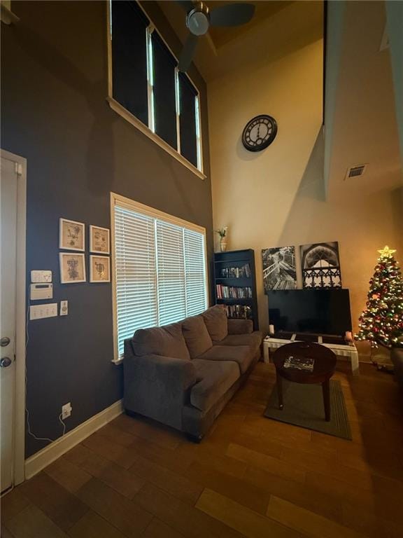 living room featuring hardwood / wood-style flooring, ceiling fan, and a high ceiling