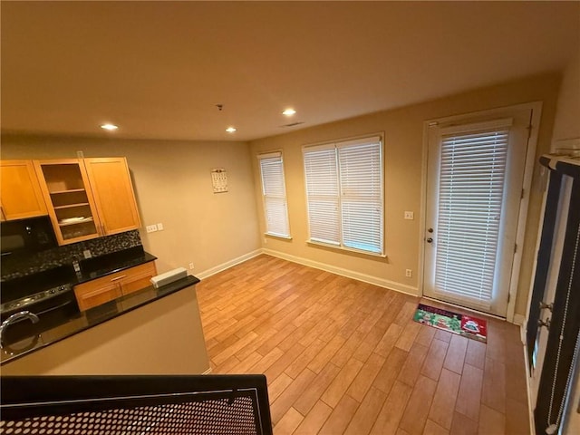 kitchen with light wood-type flooring, light brown cabinetry, and decorative backsplash