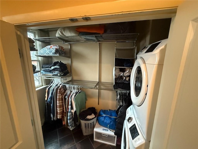 interior space featuring stacked washer / drying machine and dark tile patterned floors