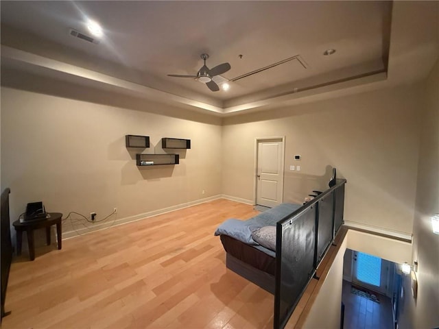 home theater room with a raised ceiling, hardwood / wood-style floors, and ceiling fan