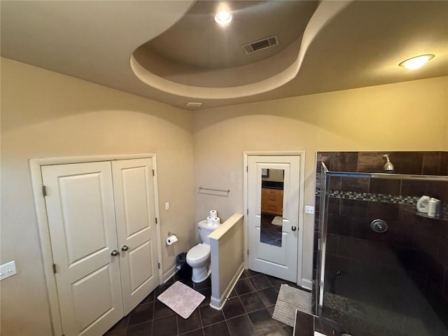 bathroom with a tray ceiling, tile patterned floors, toilet, and walk in shower