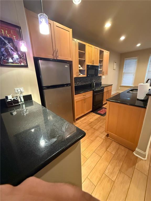 kitchen with decorative light fixtures, tasteful backsplash, sink, stainless steel fridge, and dark stone counters