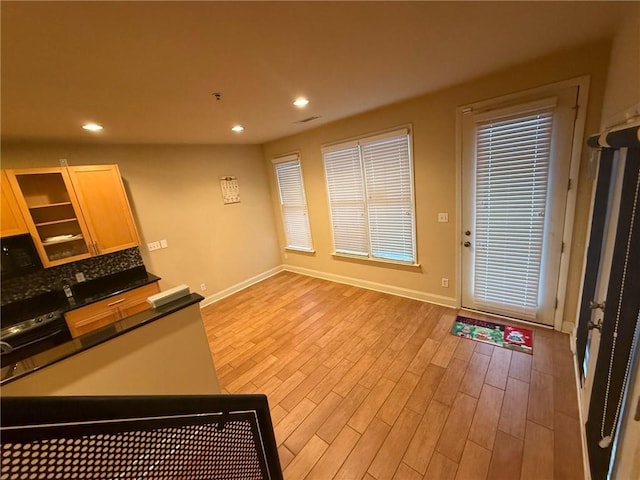 kitchen with light brown cabinets, decorative backsplash, and light hardwood / wood-style flooring