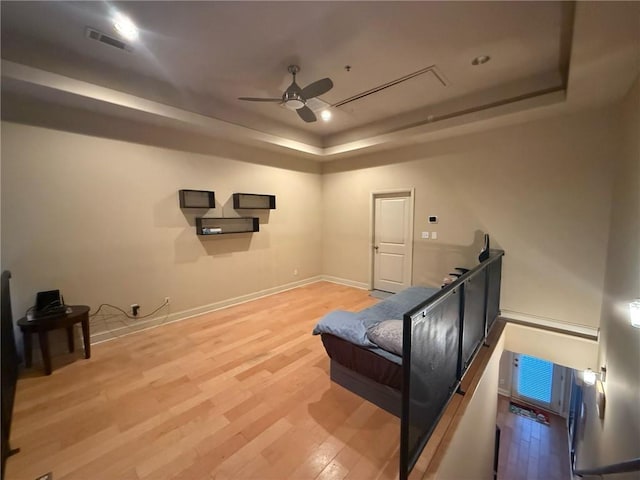 interior space with hardwood / wood-style flooring, ceiling fan, and a tray ceiling