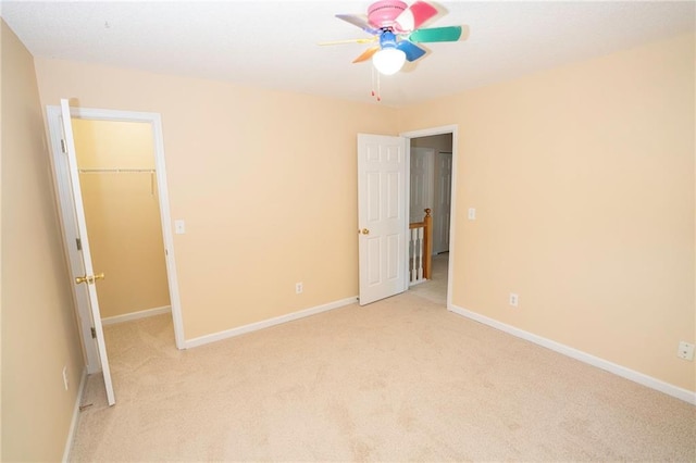 unfurnished bedroom with ceiling fan, light colored carpet, a closet, and a walk in closet