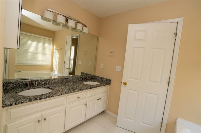 bathroom with tile patterned floors, a tub to relax in, and vanity