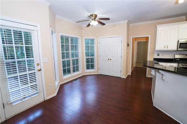 kitchen featuring ceiling fan, stainless steel appliances, dark wood-type flooring, white cabinetry, and backsplash