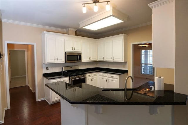 kitchen featuring ornamental molding, kitchen peninsula, dark wood-type flooring, white cabinetry, and stainless steel appliances