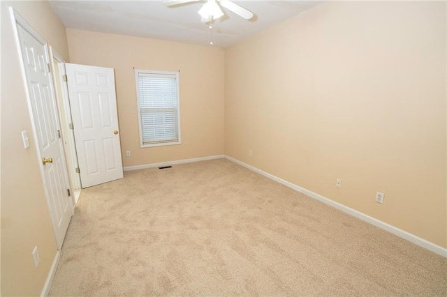 spare room with ceiling fan and light colored carpet