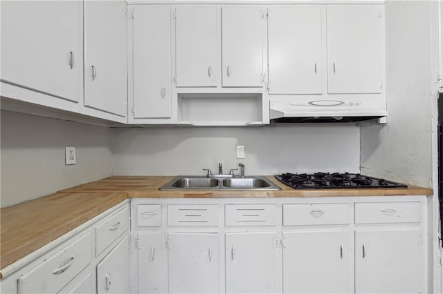 kitchen featuring white cabinetry, under cabinet range hood, light countertops, a sink, and black gas cooktop