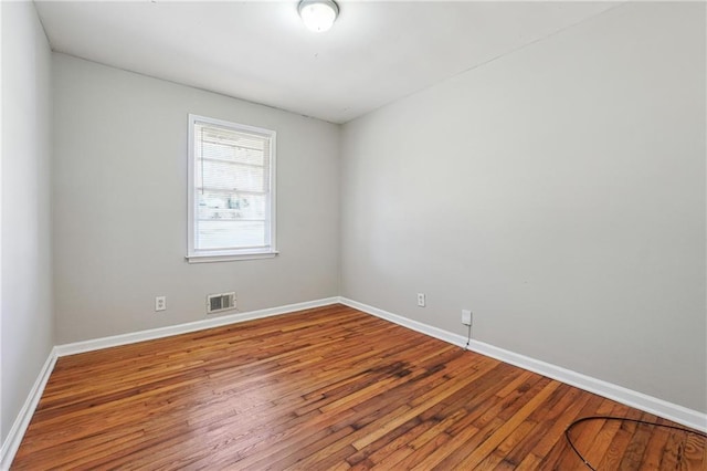 spare room featuring visible vents, baseboards, and hardwood / wood-style flooring