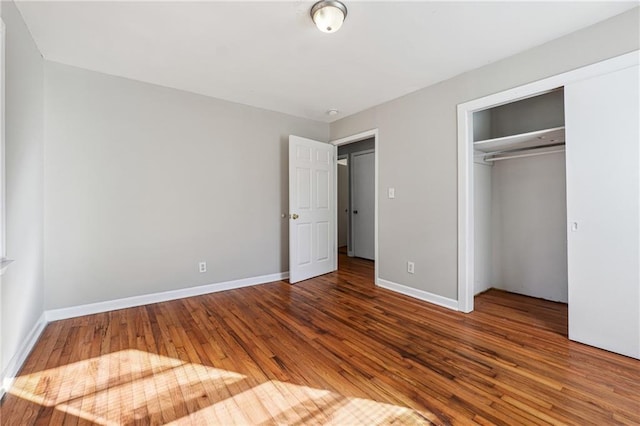 unfurnished bedroom featuring a closet, wood-type flooring, and baseboards