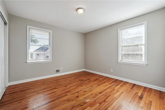 empty room featuring light wood-style floors, baseboards, and visible vents