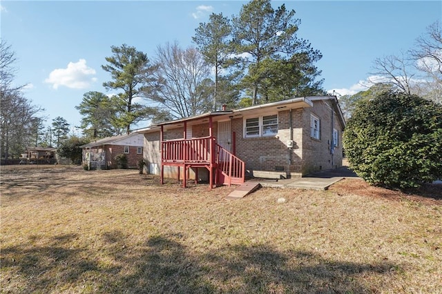 rear view of house featuring brick siding and a yard