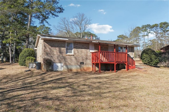 back of house featuring brick siding, crawl space, and a lawn