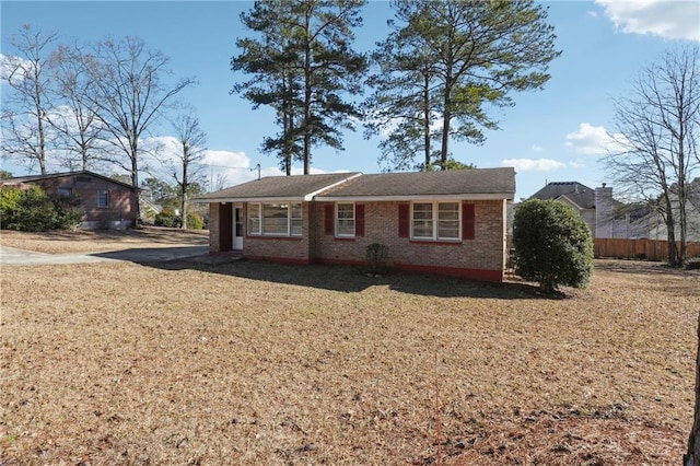 ranch-style home featuring a front yard, fence, and brick siding