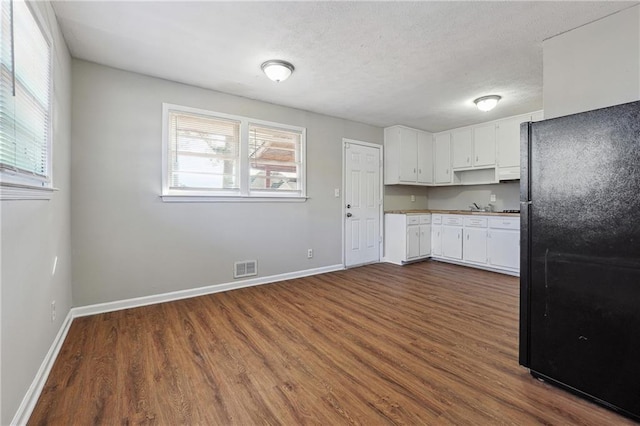 kitchen with white cabinets, visible vents, freestanding refrigerator, and a healthy amount of sunlight