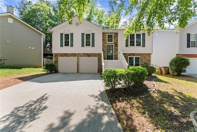 split foyer home featuring an attached garage, concrete driveway, and stone siding