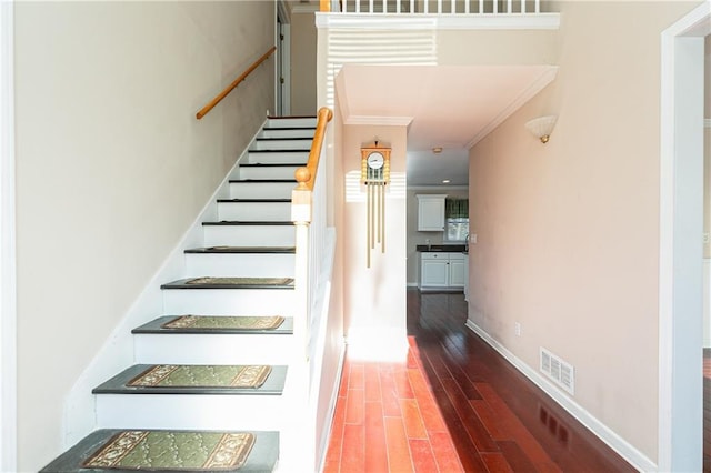 stairs featuring crown molding and wood-type flooring