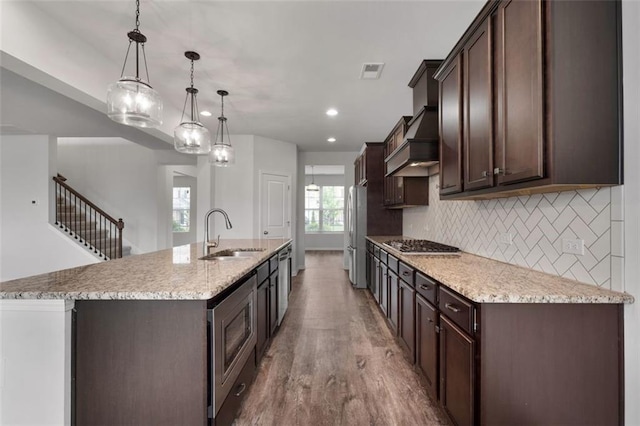 2537 Sori Dr, Buford, GA 30519 - kitchen with a sink, premium range hood, dark brown cabinetry, wood finished floors, and a center island with sink