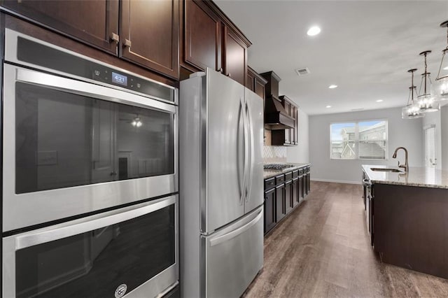 2537 Sori Dr, Buford, GA 30519 - kitchen with appliances with stainless steel finishes, custom exhaust hood, a sink, wood finished floors, and dark brown cabinetry