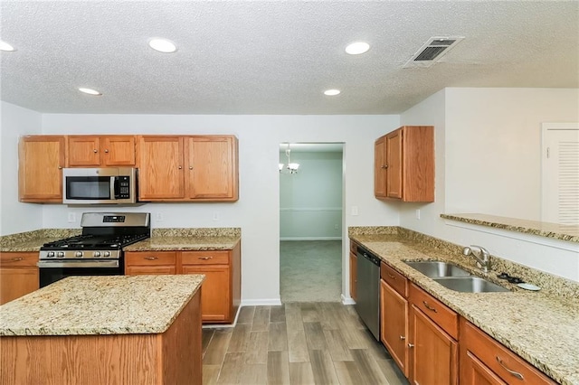 137 Legend Creek Dr, Canton, GA 30114 - kitchen with stainless steel appliances, a sink, wood finished floors, a textured ceiling, and light stone countertops