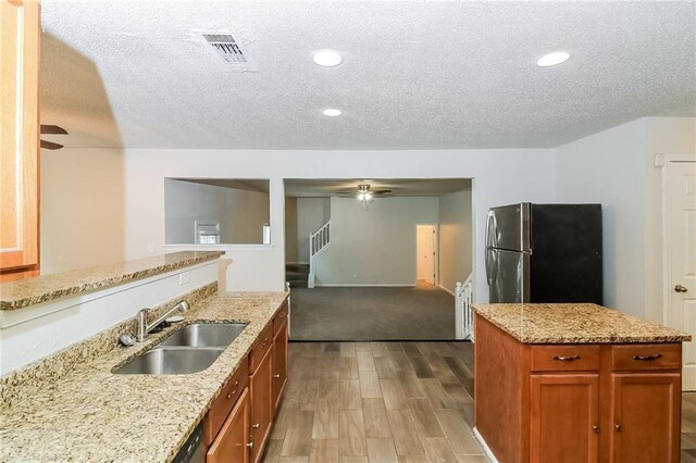 137 Legend Creek Dr, Canton, GA 30114 - kitchen featuring freestanding refrigerator, a sink, light wood-style flooring, a textured ceiling, and brown cabinetry