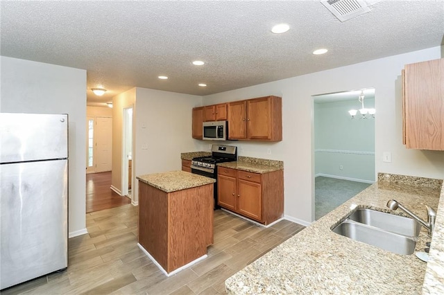 137 Legend Creek Dr, Canton, GA 30114 - kitchen with appliances with stainless steel finishes, a sink, a center island, a textured ceiling, and light wood-type flooring