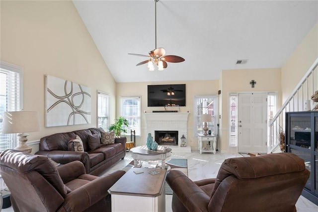 living room with a wealth of natural light, marble finish floor, a fireplace, and a ceiling fan