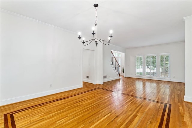 unfurnished living room featuring crown molding, baseboards, light wood-type flooring, and a chandelier