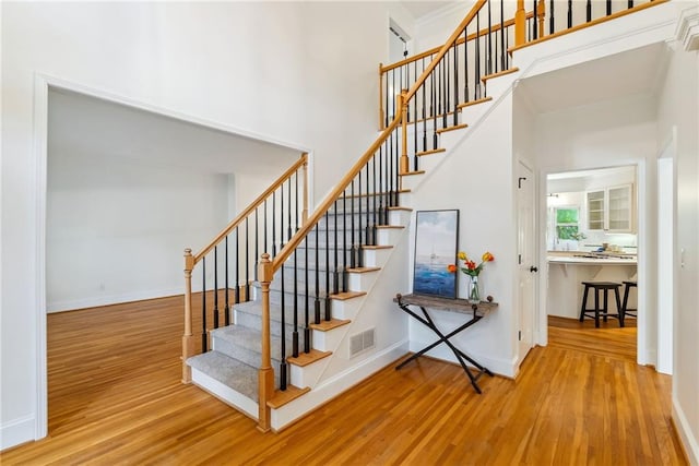 stairway with baseboards, visible vents, and wood finished floors