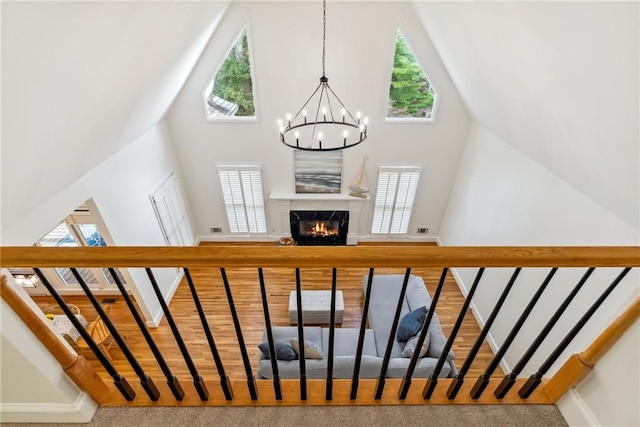 staircase with baseboards, a premium fireplace, a notable chandelier, and high vaulted ceiling